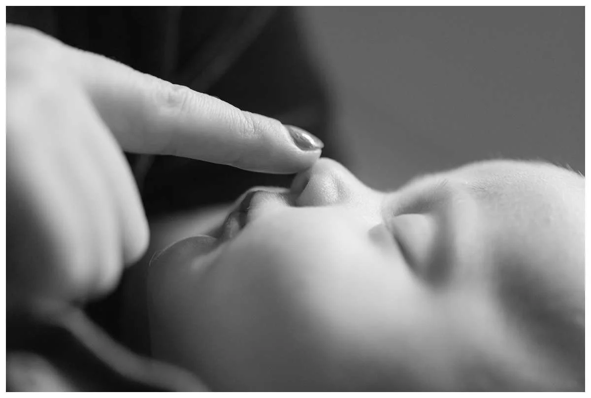 Profile of baby girl with mom's finger caresing her nose