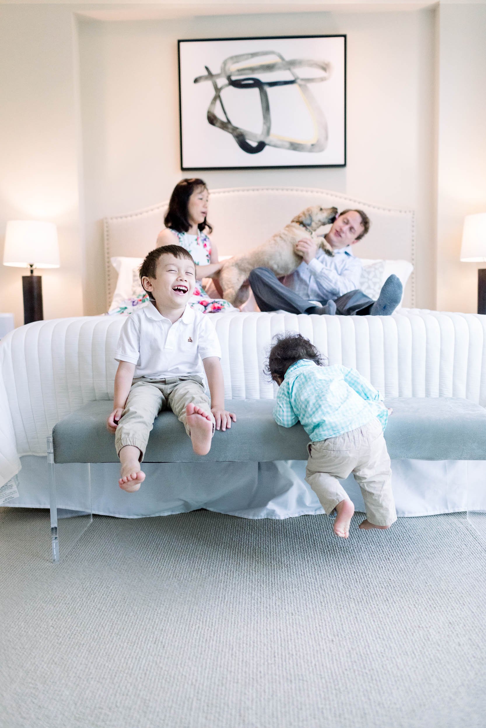 Boys giggling in the foreground with parents sitting behind being kissed by family dog
