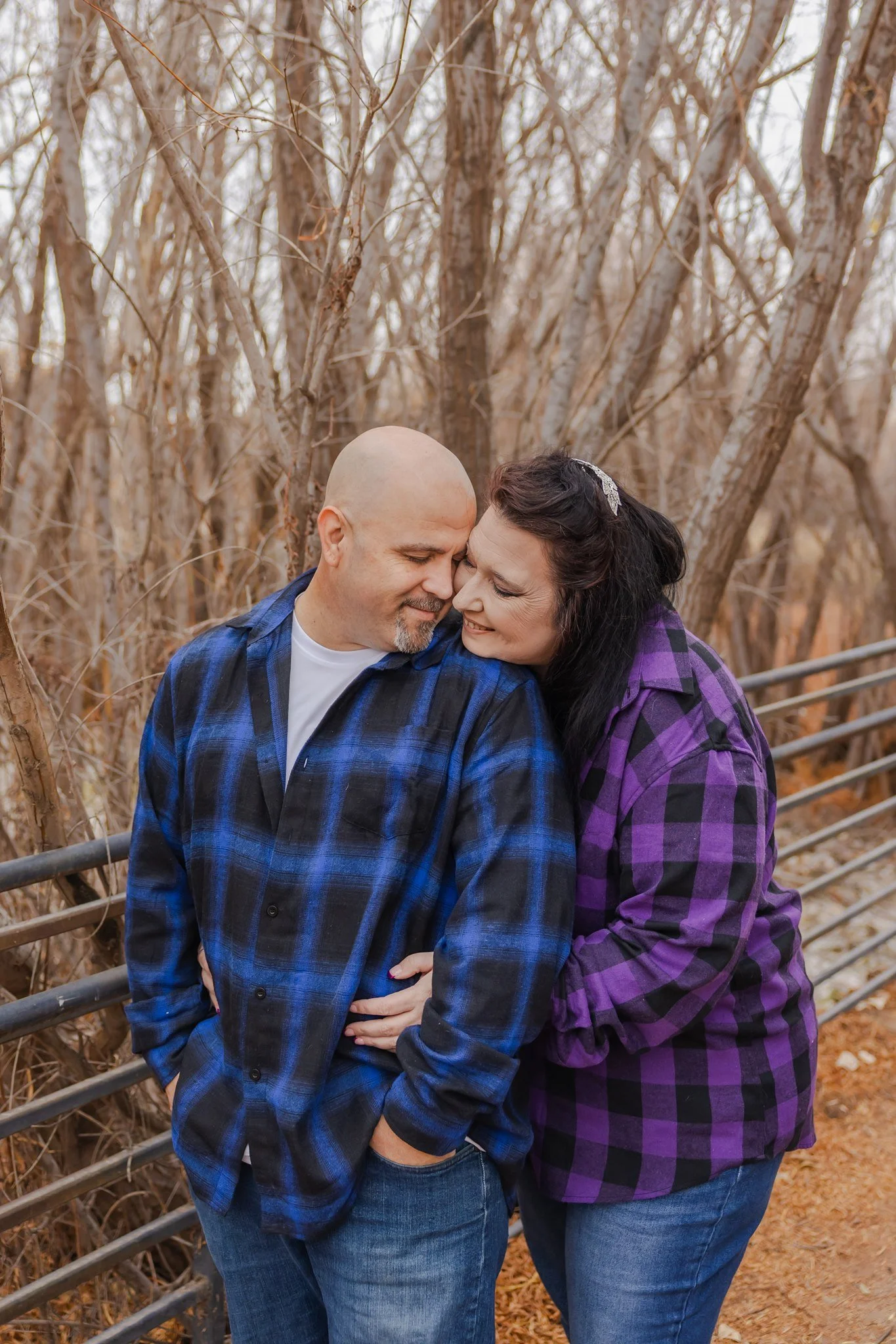 An El Paso, Texas couple embracing each other at Rio Bosque Park in Socorro wearing plaid outfits and celebrating their engagement.