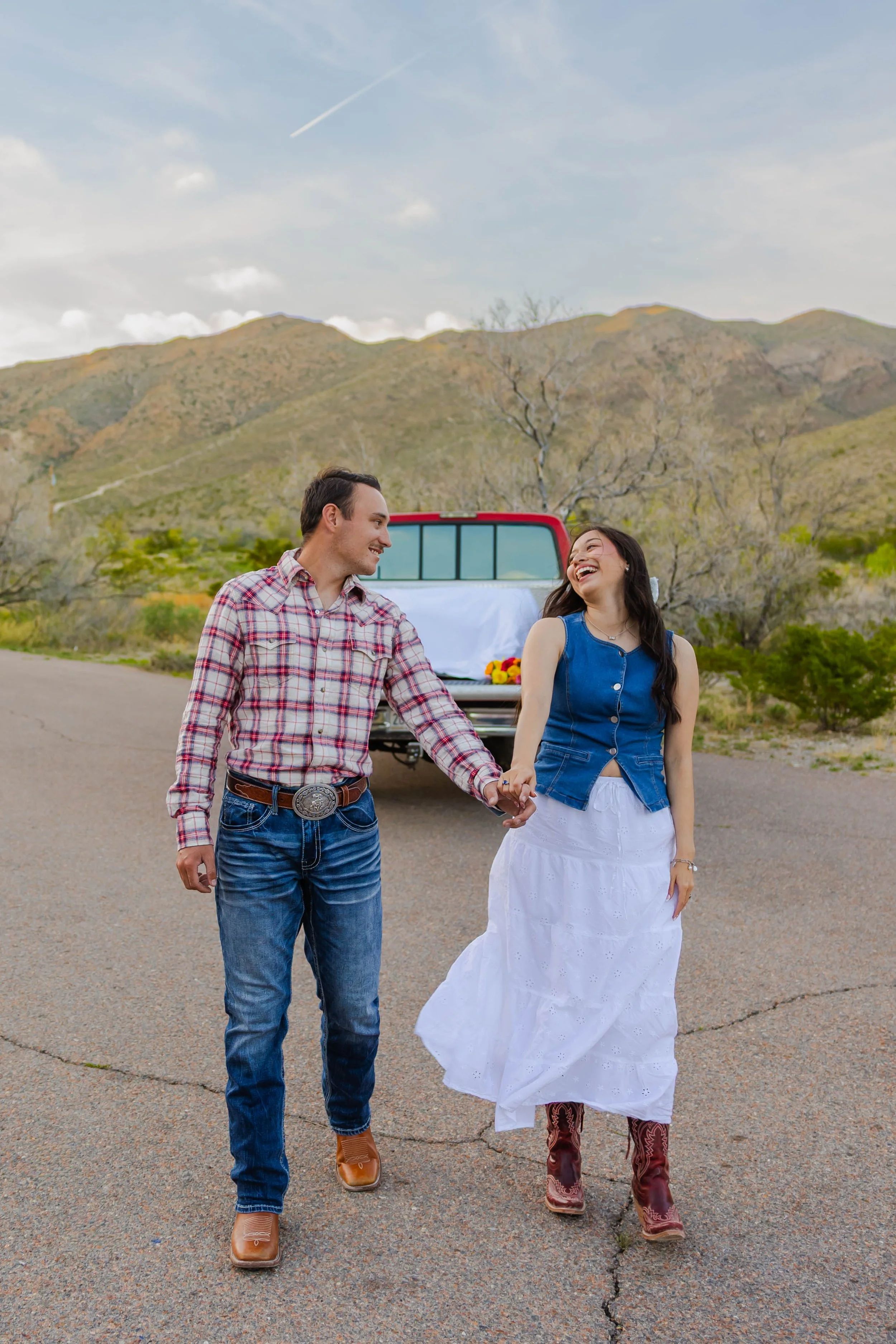  Couple walking hand in hand through McKelligon Canyon with Franklin Mountains in the background 