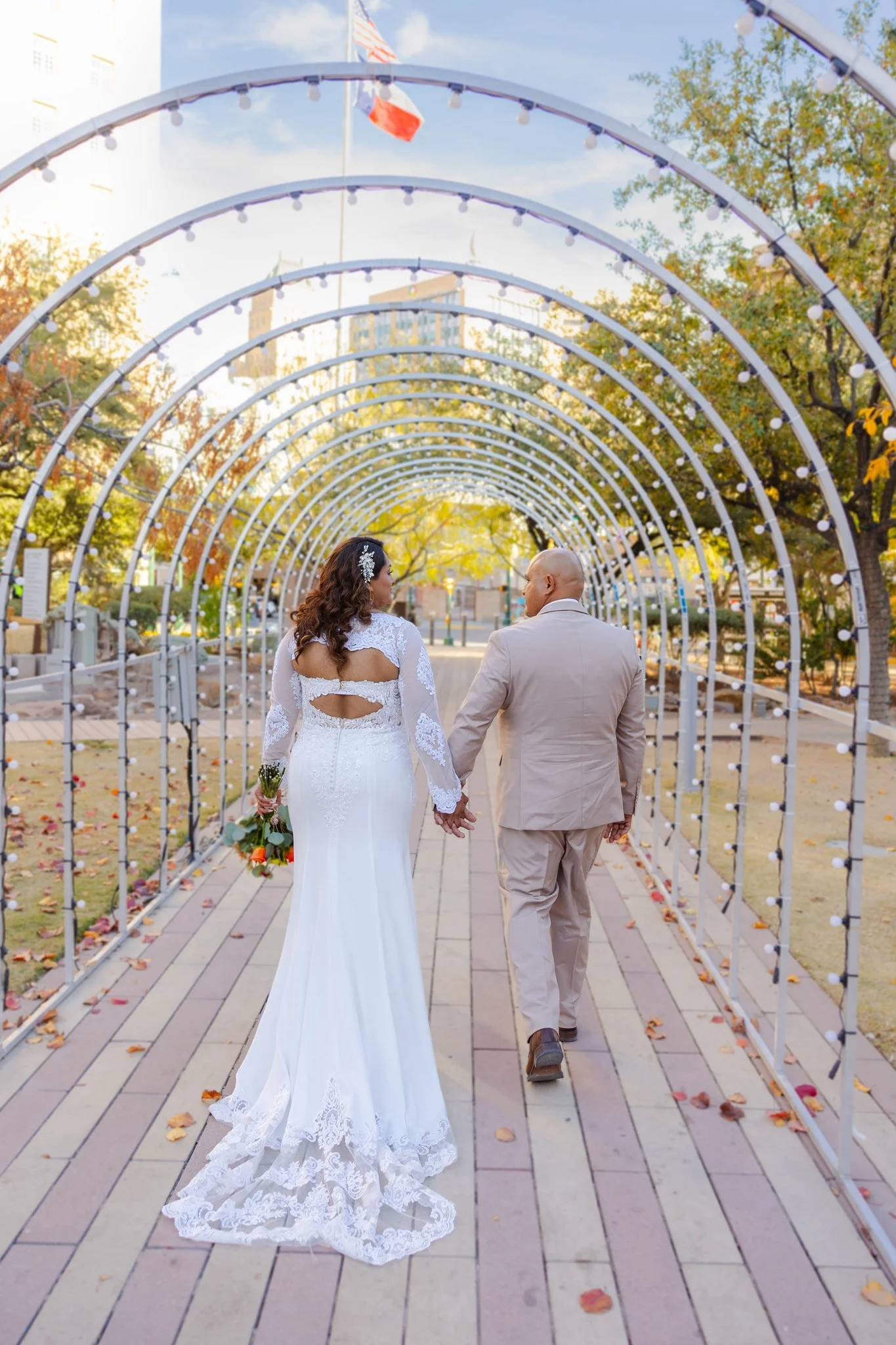 A bride and groom holding hands and walking through Downtown El Paso, Texas during Winterfest.