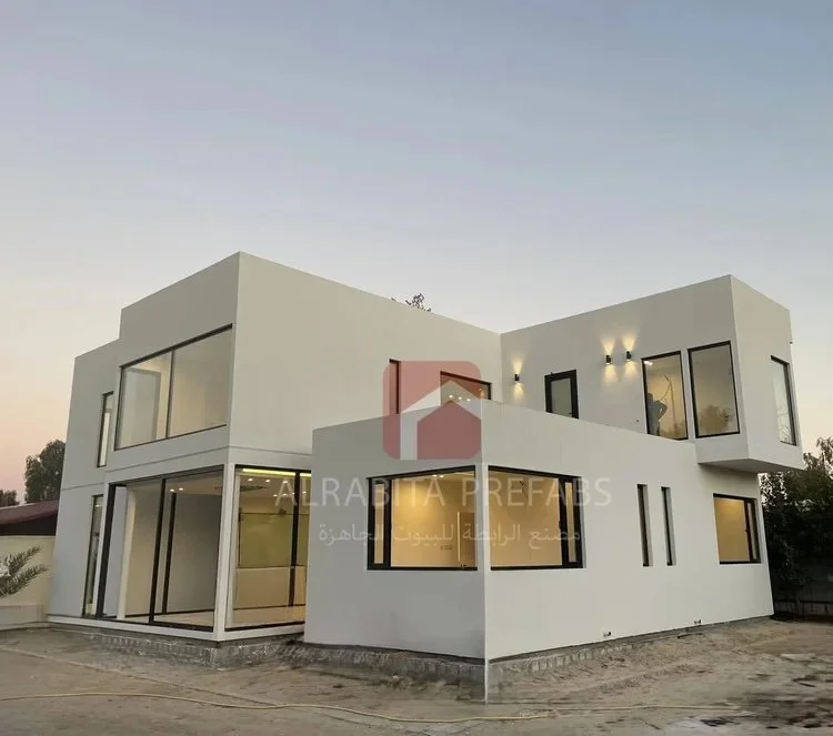 Modern two-story house with large glass windows and exterior lights executed by Alrabita Prefab Co. بيت دورين مودرن مع شبابيك كبيرة واضاءة خارجية تم تنفيذه من قبل مصنع الرابطة للبيوت الجاهزة