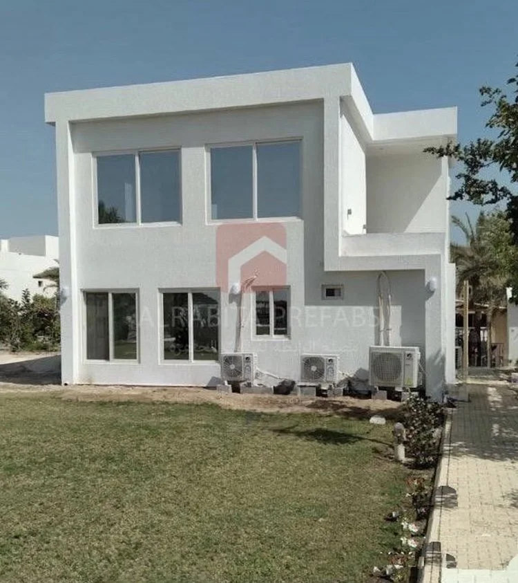 White modern two-story prefabricated house with large windows executed by Alrabita Prefab Co. بيت جاهز دورين بتصميم مودرن مع شبابيك كبيرة تم تنفيذه من قبل مصنع الرابطة للبيوت الجاهزة