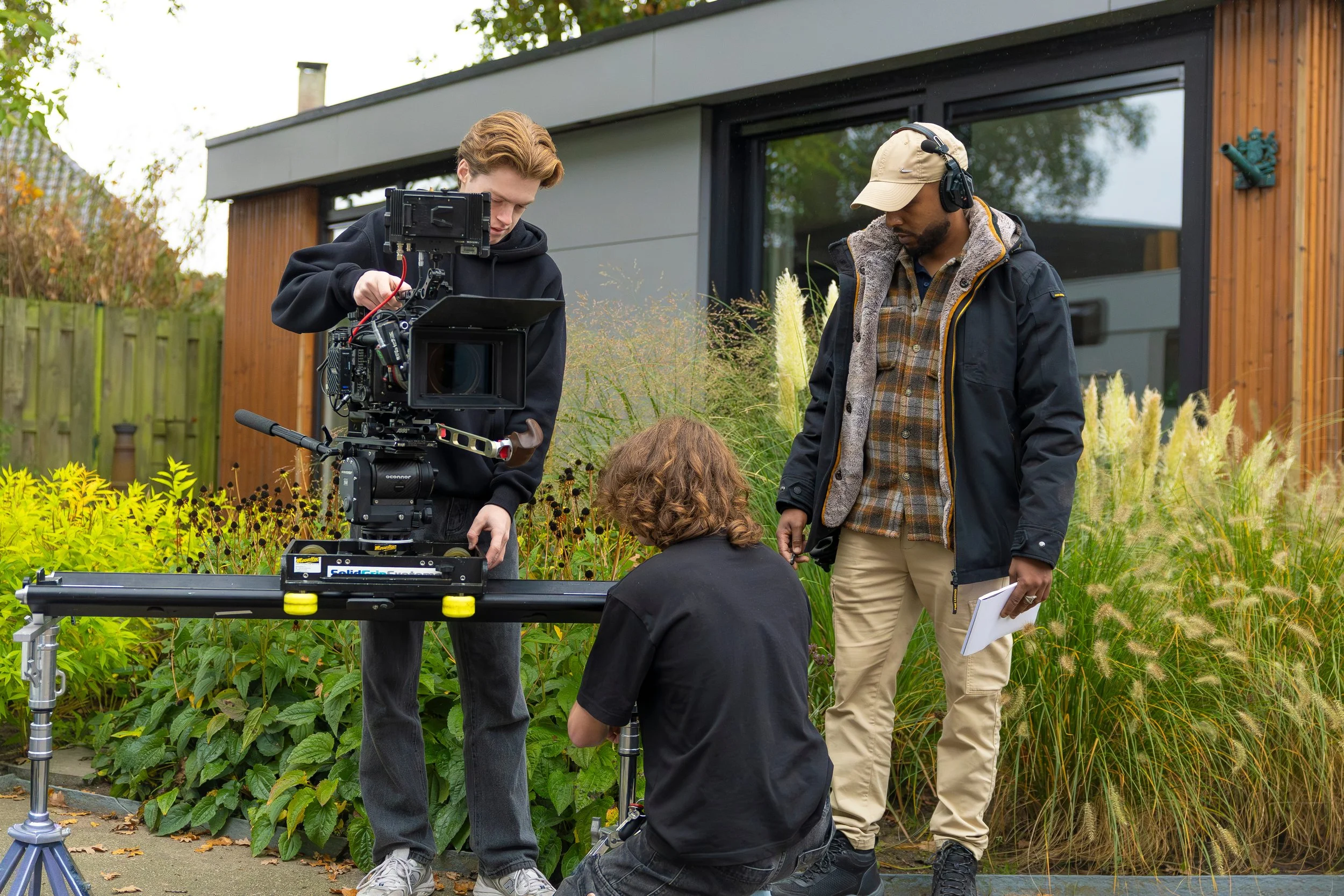 Filmmaking crew setting up camera equipment outdoors