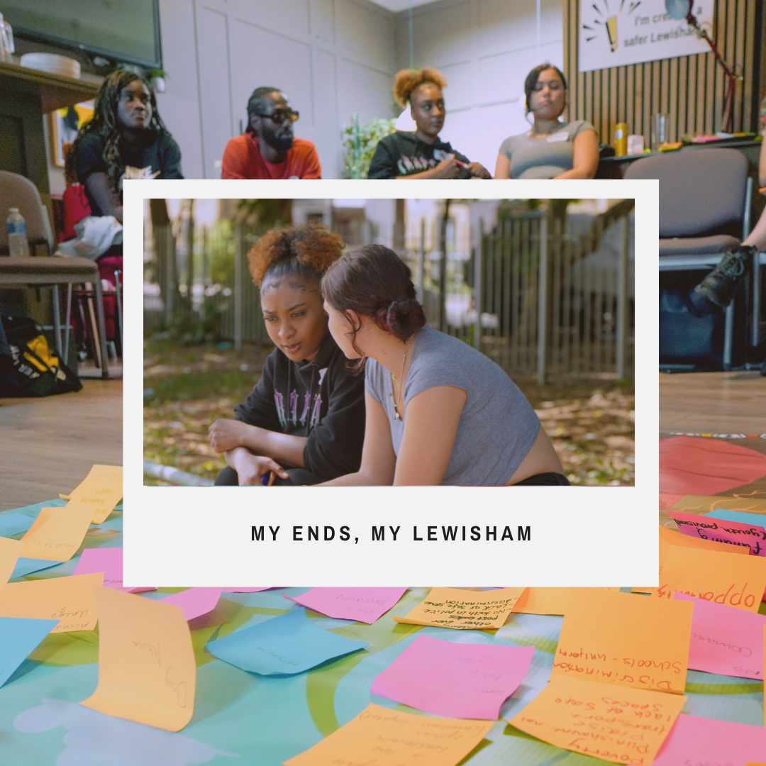 Two women sitting outdoors engaging in a serious conversation with a group of people in meetings or workshops. In the background, there's an indoor meeting room with several women sitting and listening. The foreground has scattered colorful sticky notes, and a overlay caption reads "My Ends, My Lewisham."