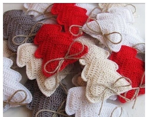a pile of crochet christmas trees in red, white, ivory, and gray