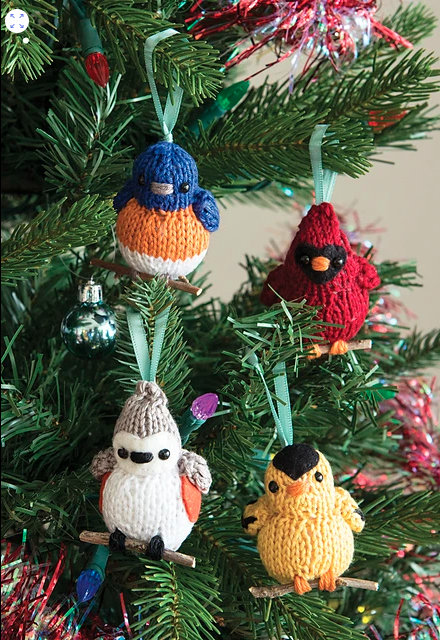 four knit bird ornaments hanging on a tree