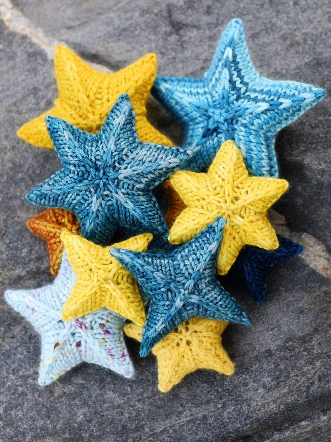 collection of blue, yellow, rust, and light blue knit stars