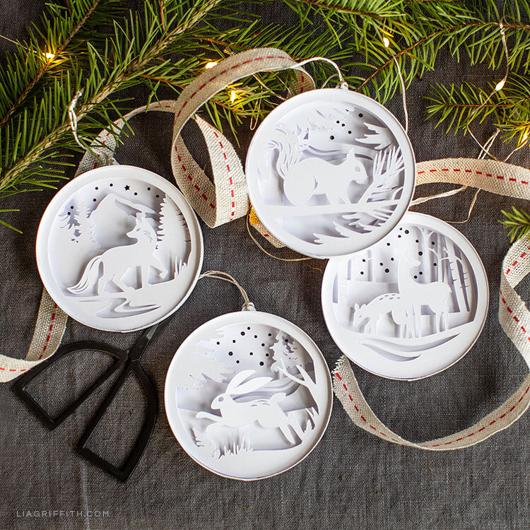 white paper cutout ornaments of woodland scenes