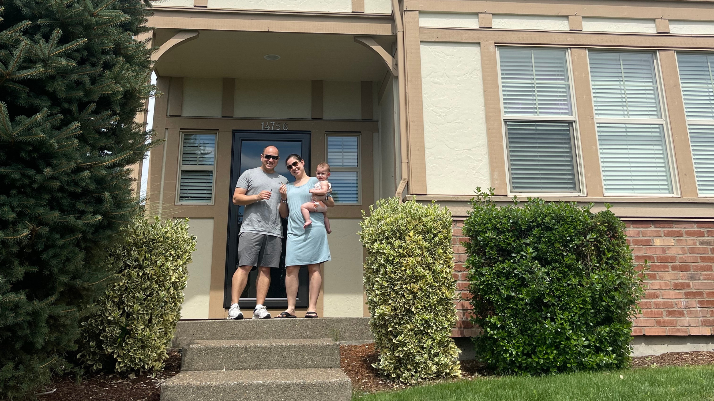 Mother, father, and baby on the steps of their new home
