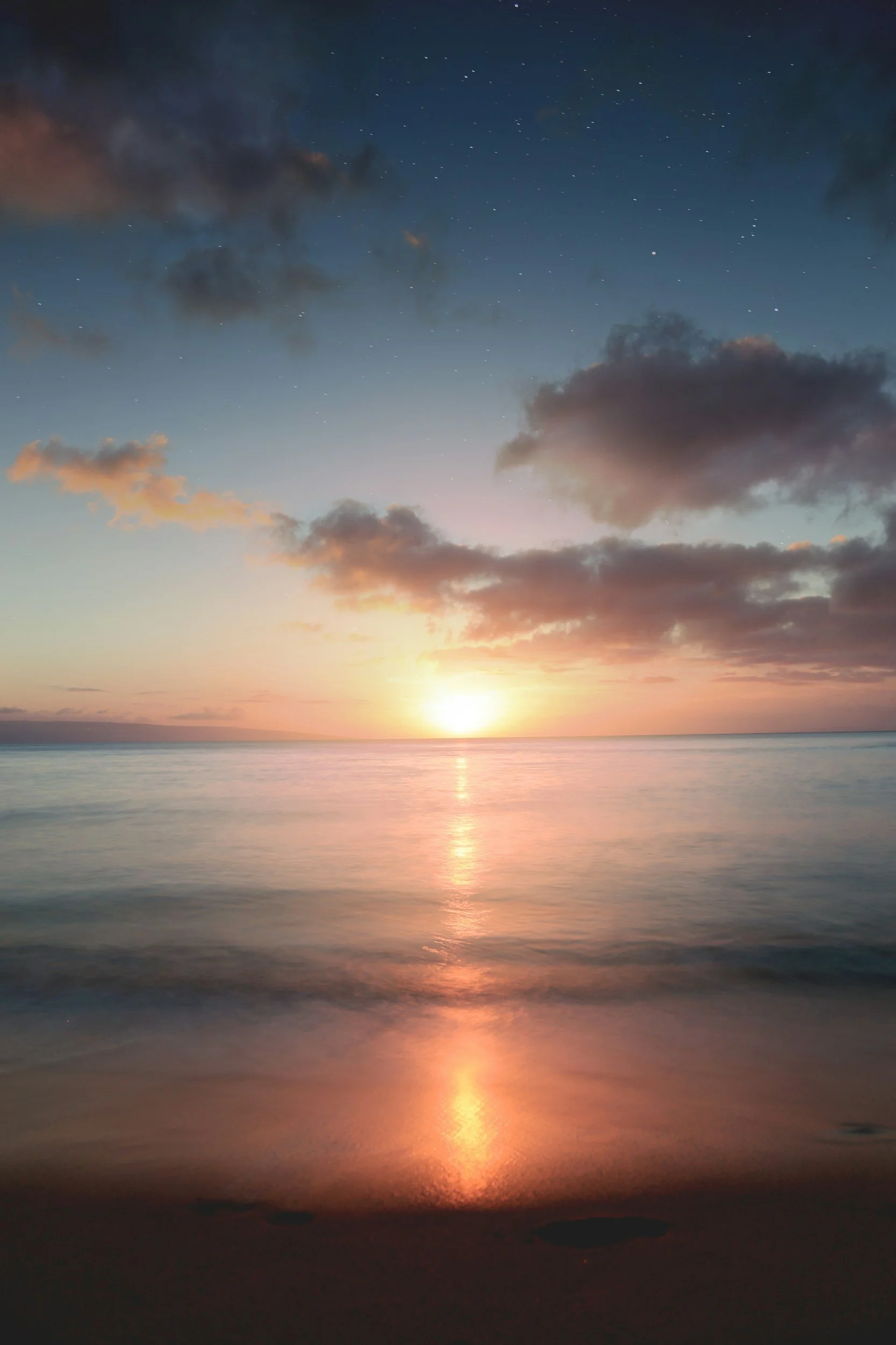 Sunset over ocean with stars visible, reflecting on calm water, and clouds illuminated by the setting sun.