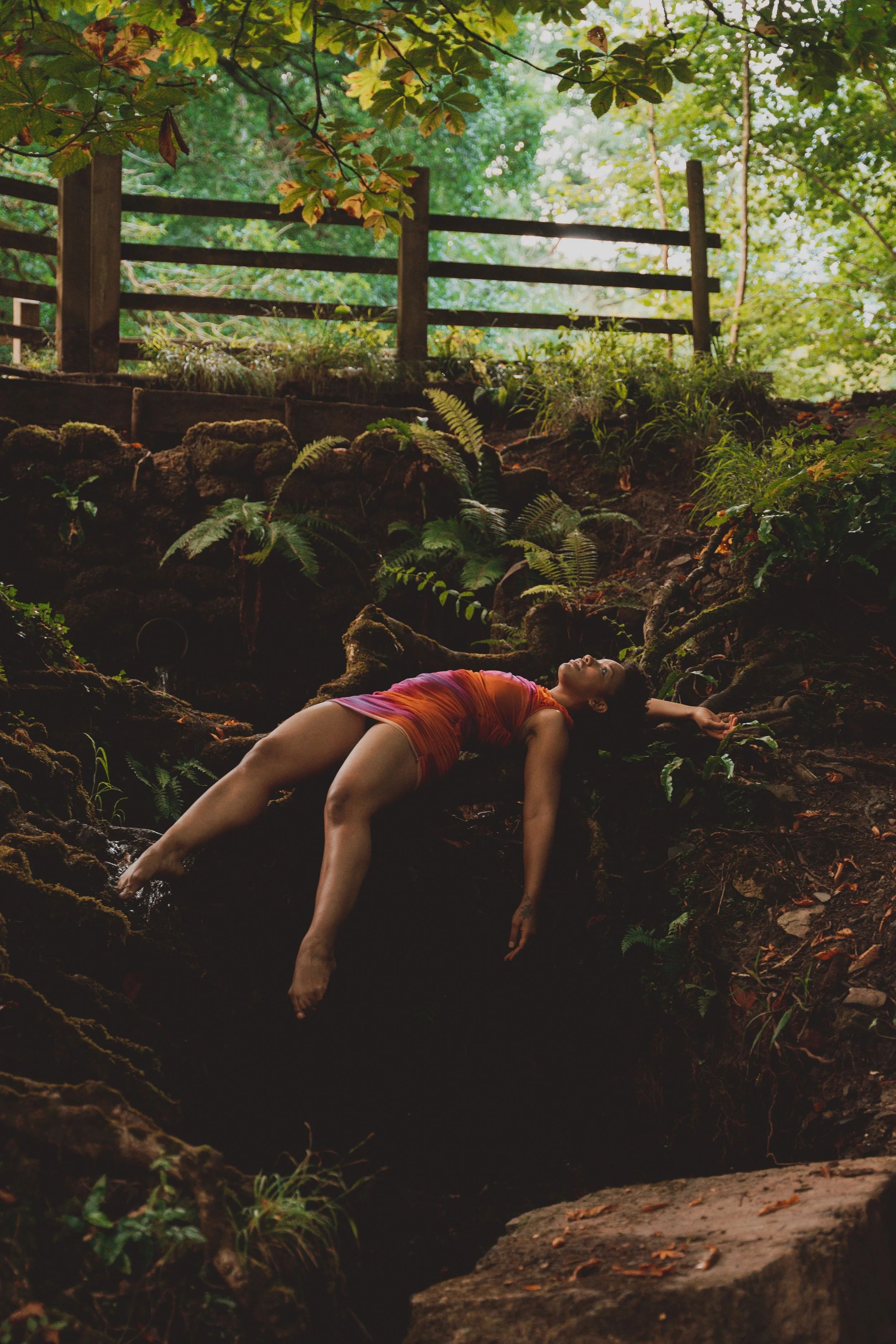 She lays on her back along a log, balanced on an embankment. Her arms and legs are visions of smooth brown skin hanging through the air as she gazes up at the sky.