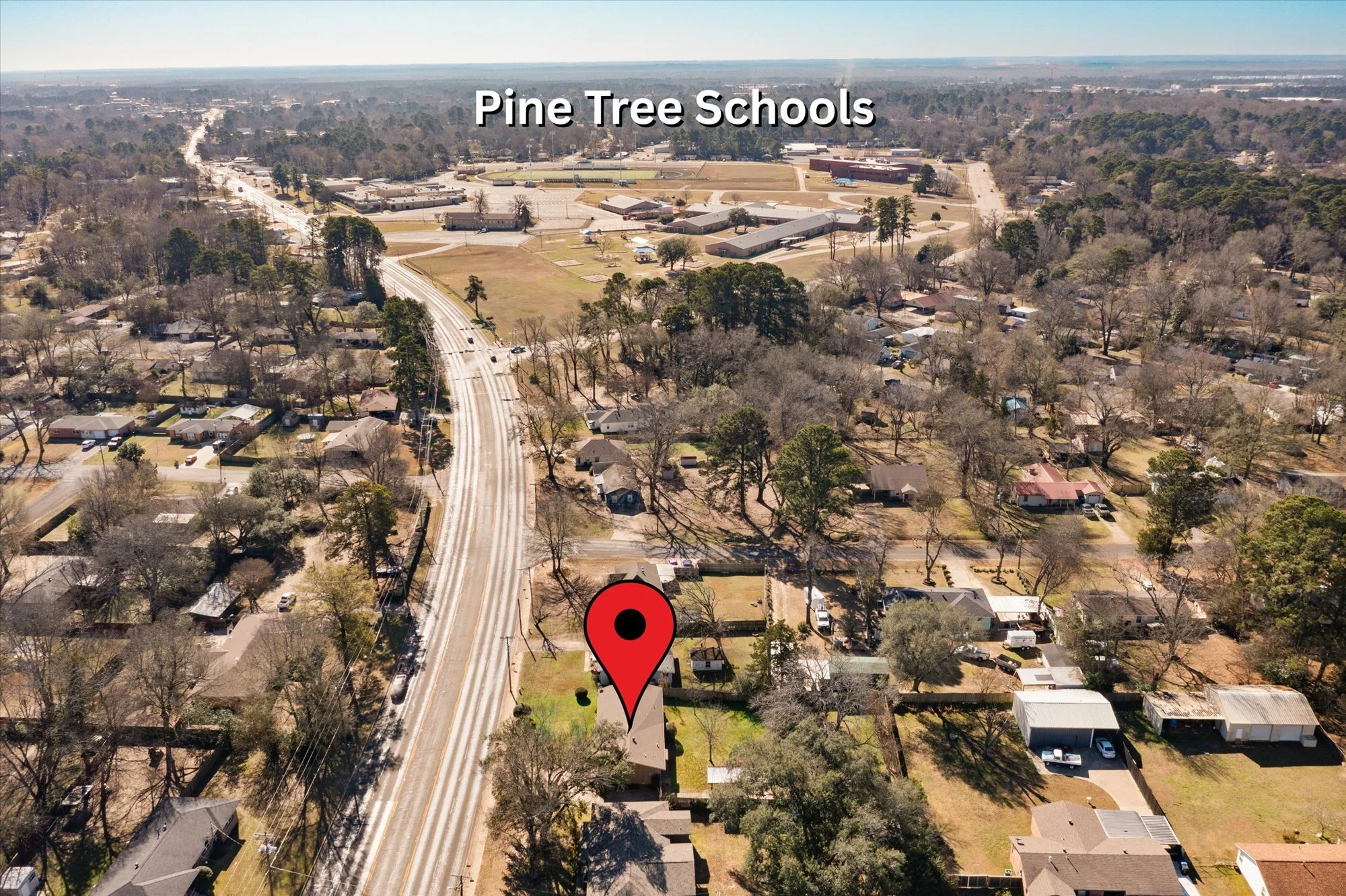 Aerial view of Pine Tree Schools campus and surrounding residential neighborhood with houses and trees, visible roads, and parking lots in the background.