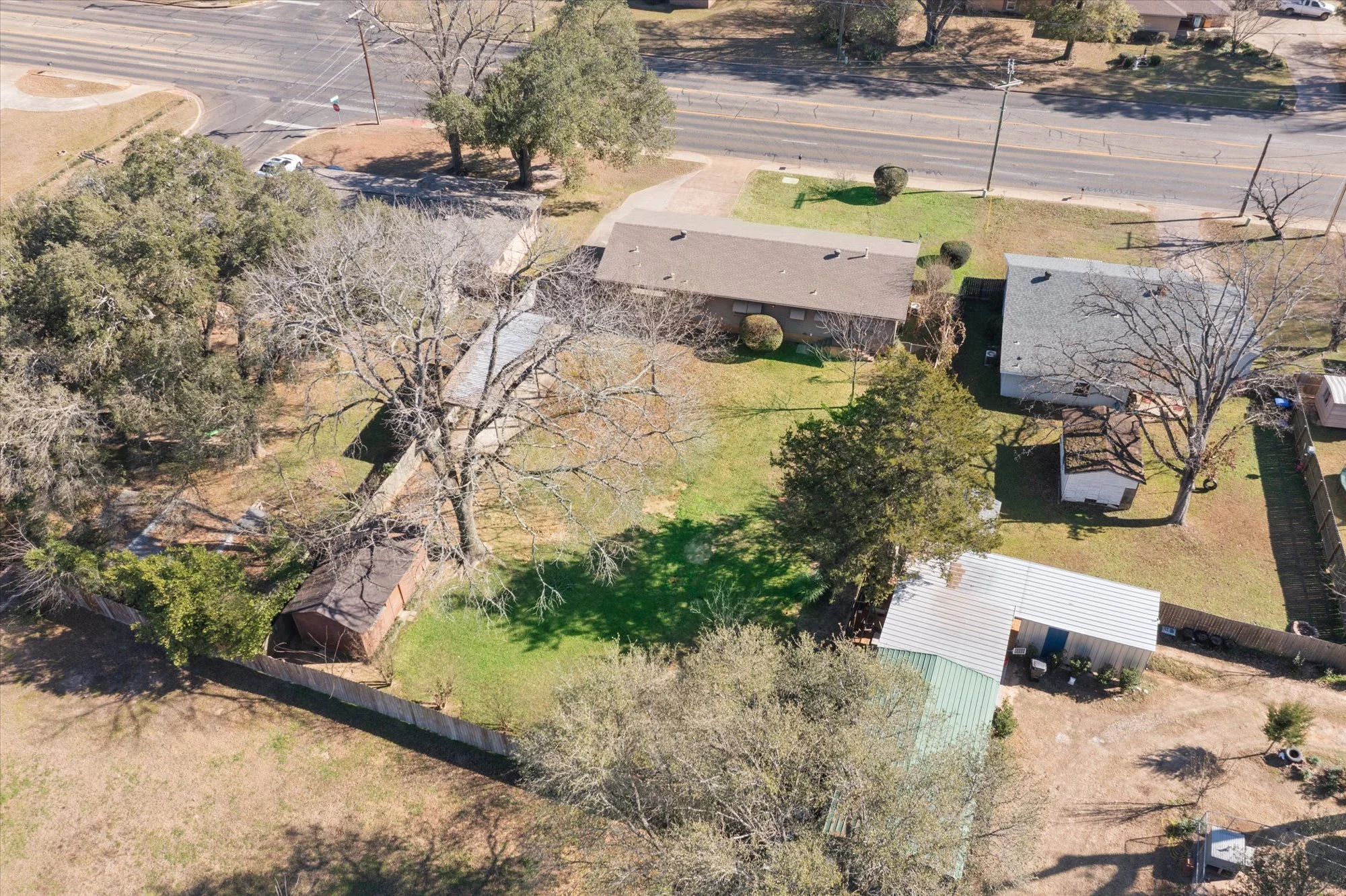 Aerial view of a residential neighborhood with several houses, trees, a street, and a yard with grass.