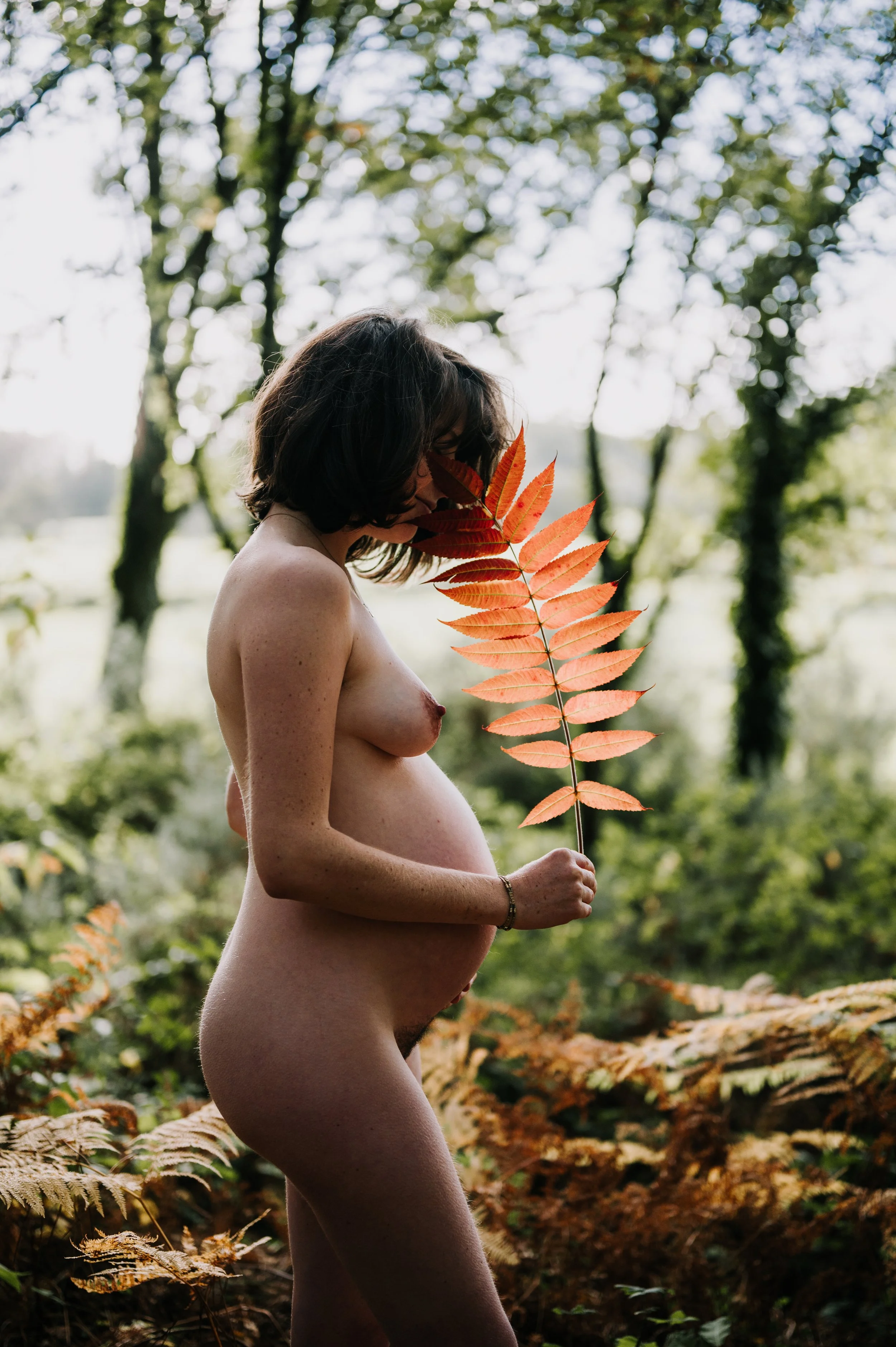 Femme nue tenant une feuille d'automne dans la forêt en automne.