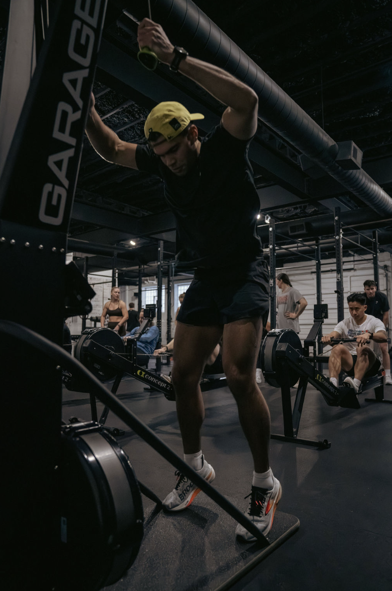 Athletes completing rowing intervals during a hybrid fitness class at The Garage Chicago in Chicago.