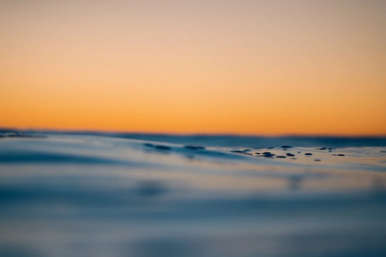 Blurry ocean surface with a sunset sky