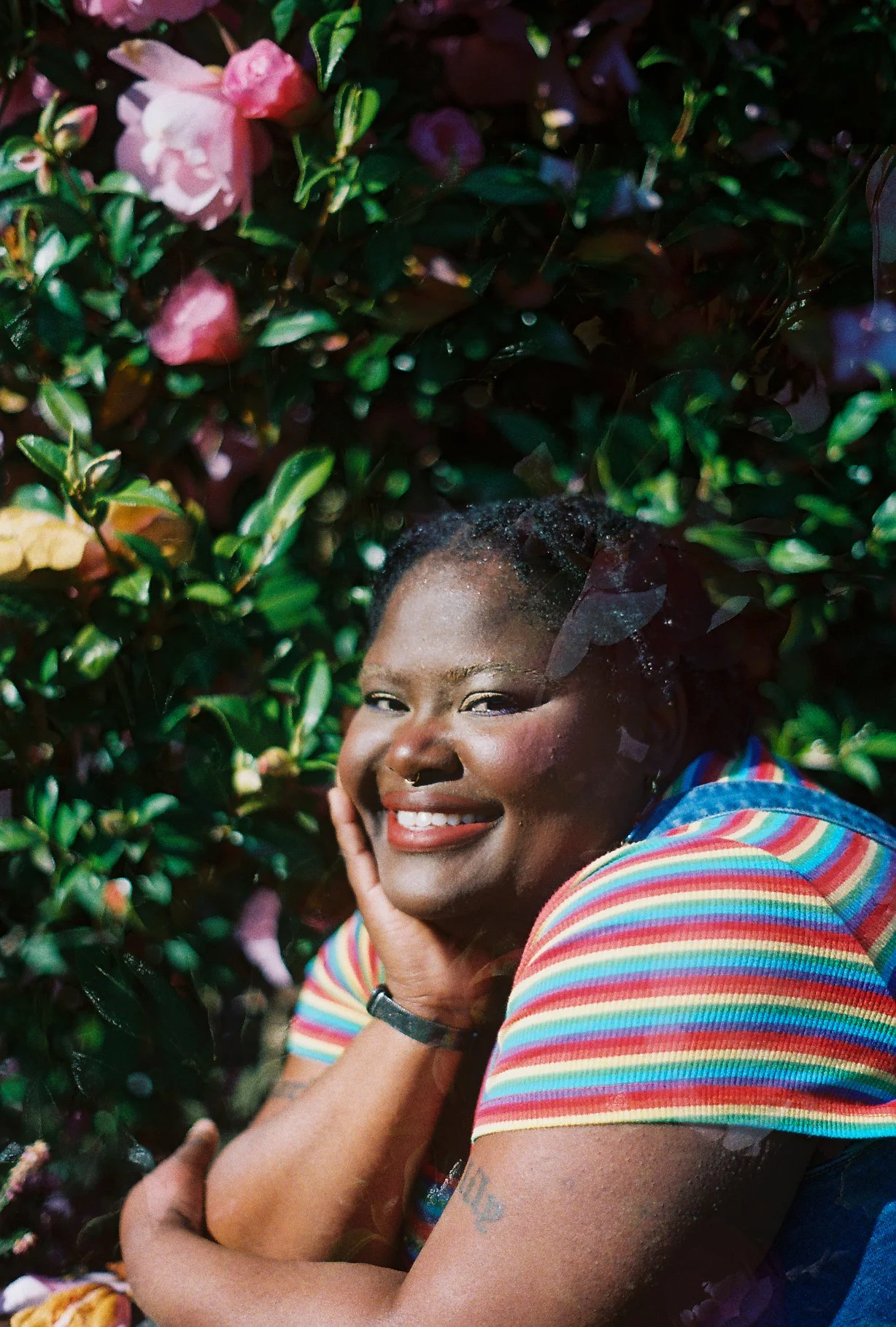 A photo of joy with her hand resting on her chin. Joy is surrounded by flowers.