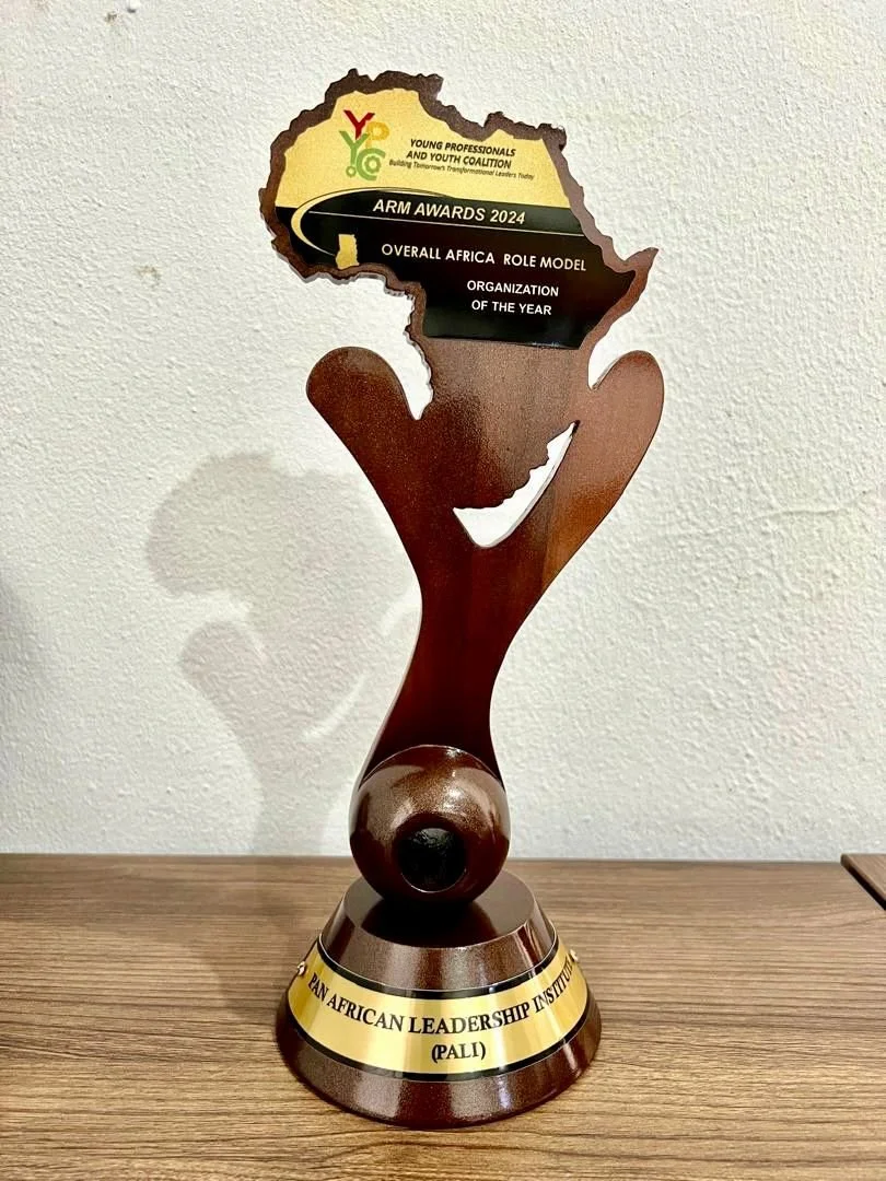 A wooden trophy award with a map of Africa at the top, inscribed with 'Young Professionals and Youth Coalition,' 'ARM Awards 2024,' 'Overall Africa Role Model,' and 'Organization of the Year.' The trophy has a circular base with a yellow band reading