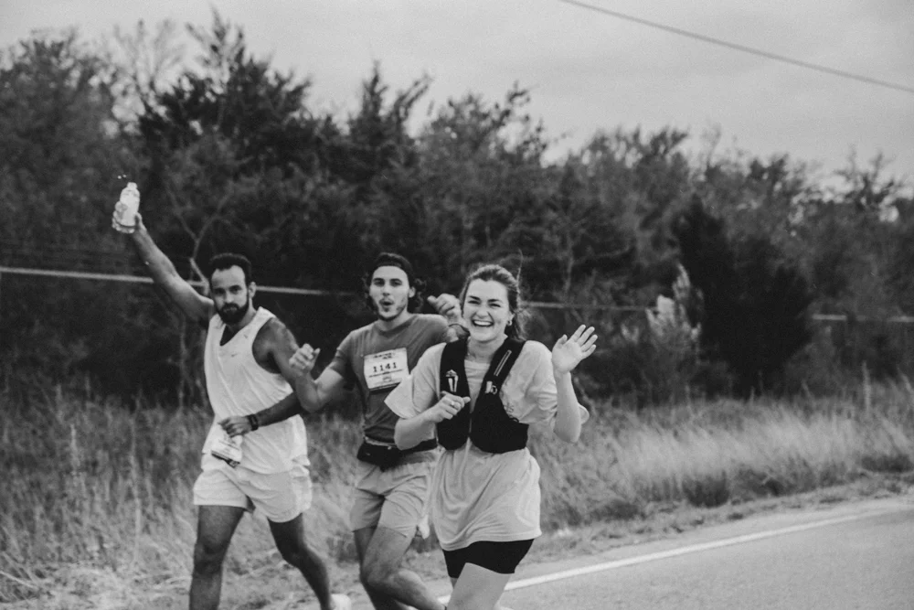 Three Justice Run runners smiling and waving on course