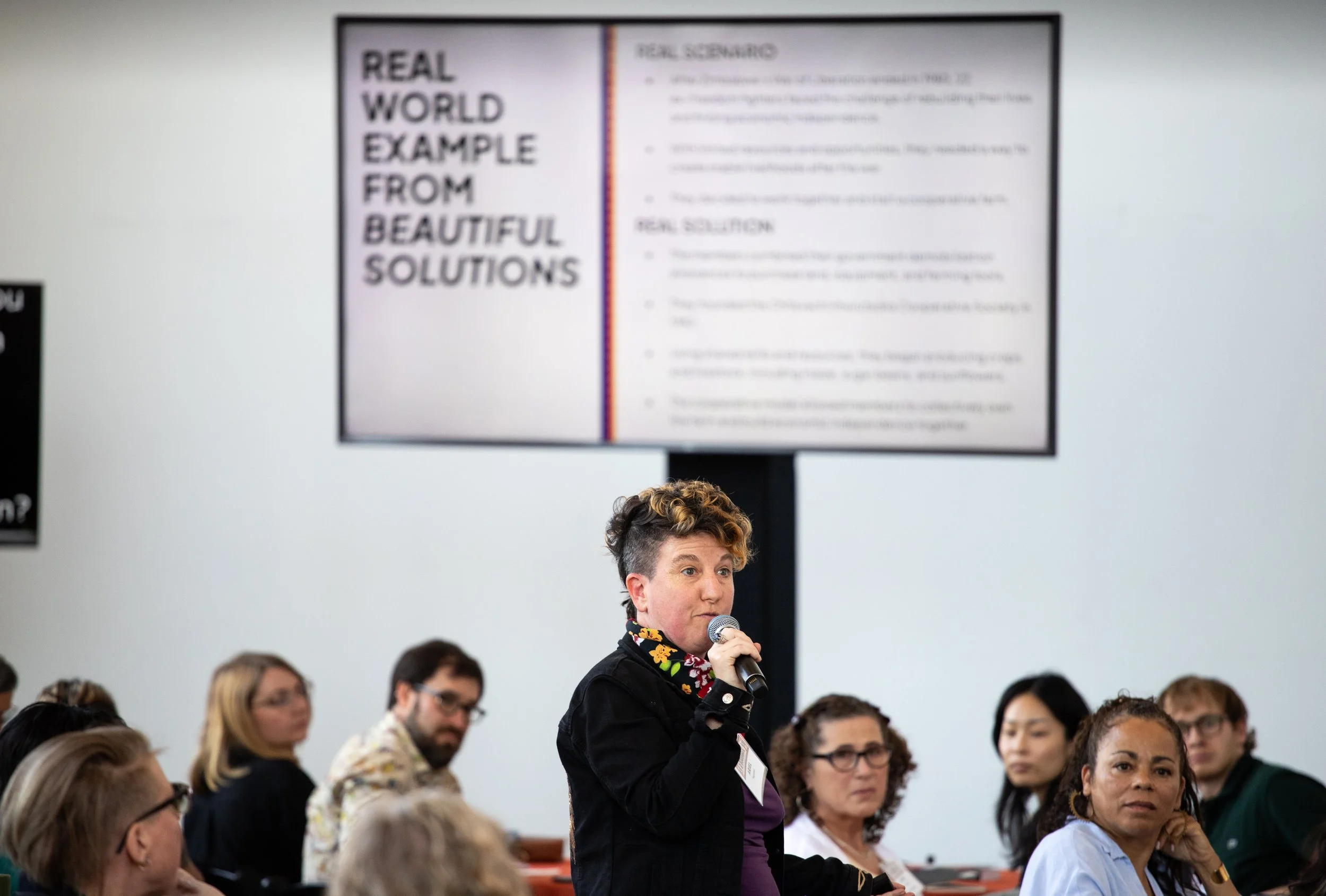 Ariel Vegosen hosting a Beautiful Solutions card set experiment, addressing a diverse crowd of organizers, artists, culture workers, and changemakers.