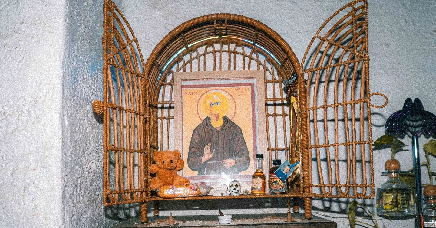 Come in, sit down, order something cold.

The shrine on the wall is ancient and old.

Big Bird has seen things. Big Bird will not say.

Just leave an offering and be on your way.