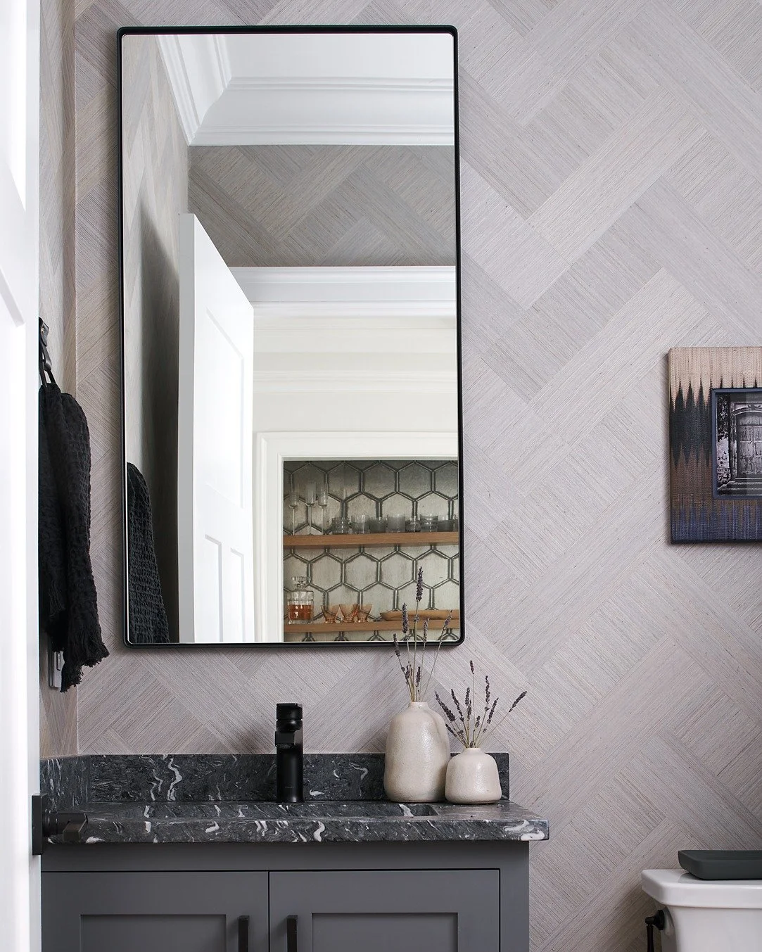 I love the layers of this monochromatic powder bathroom we did. Instead of relying on different colors, we kept to a concise color palette of cool grays and chose variation through the veining of the stone and subtle design on the wallpaper. 
Photo