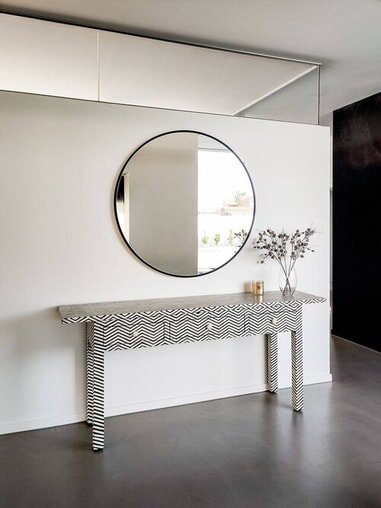 large round black frame mirror hanging in hallway over console table.jpg