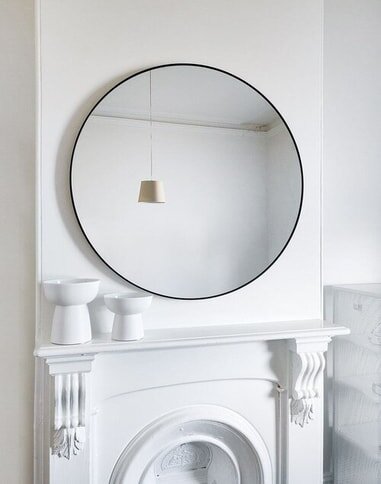 large round mirror hanging over fireplace.jpg