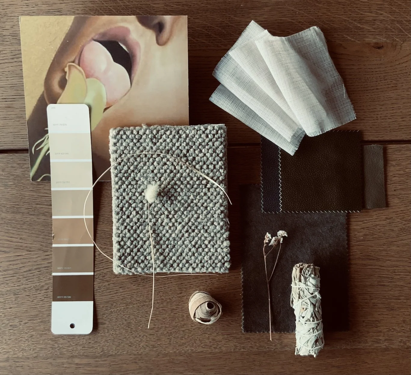 A mood board for a beige and brown color palette with fabric samples, color swatches, a knitted square with yarn, dried flowers, and rolls of string on a wooden surface.