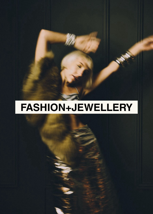 A young woman in a fur coat and shiny skirt dancing with arms raised, against a dark background, with text overlay reading "Fashion + Jewelry."