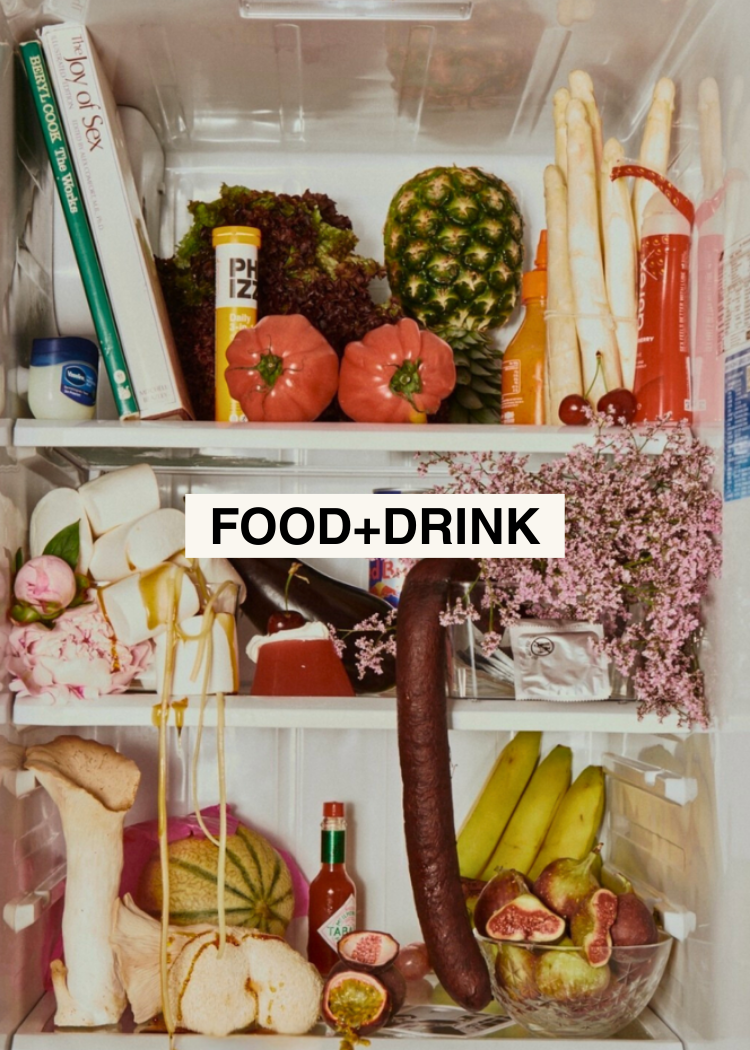 Inside of a refrigerator filled with fruits, vegetables, and food items including pineapples, tomatoes, bananas, figs, and assorted snacks, with a label reading 'FOOD+DRINK'.