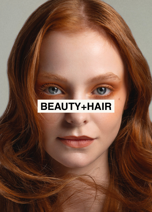Close-up of a young woman with red hair and blue eyes, with the text 'BEAUTY+HAIR' over her face.