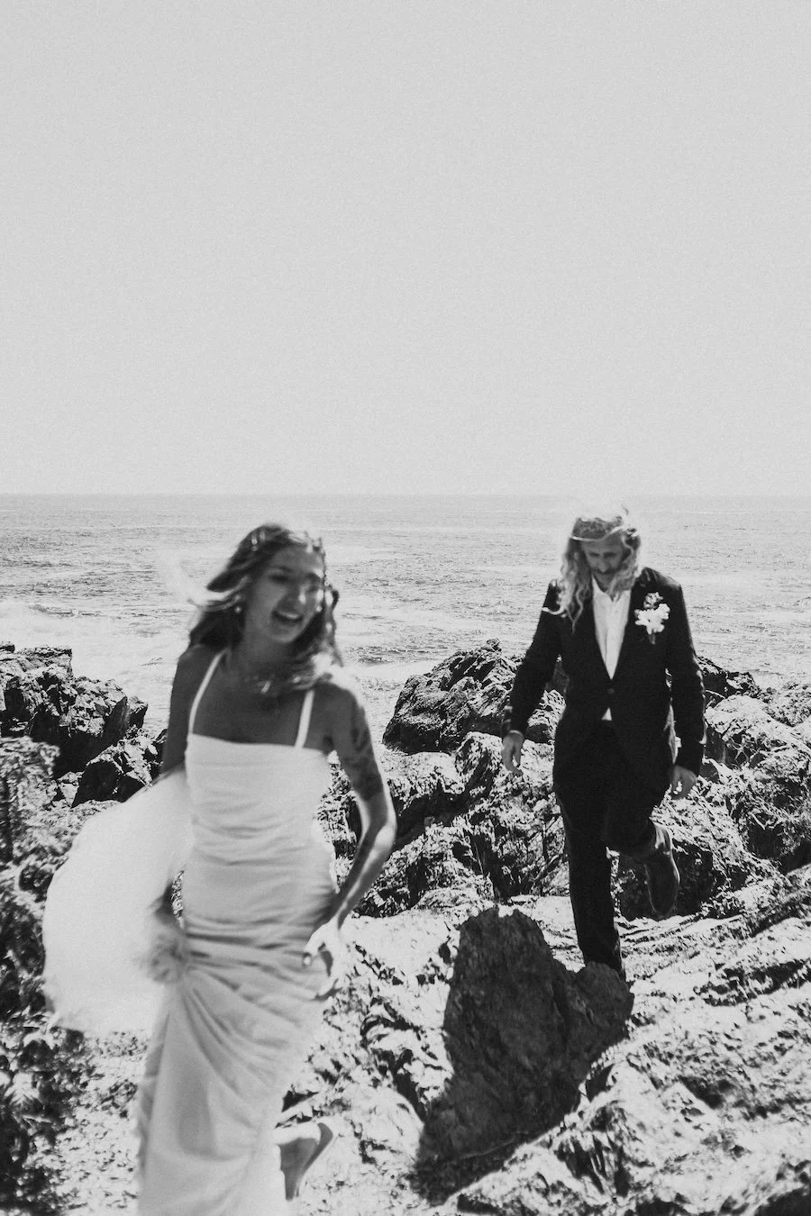 Bride and groom laughing on a rocky shoreline in Ucluelet