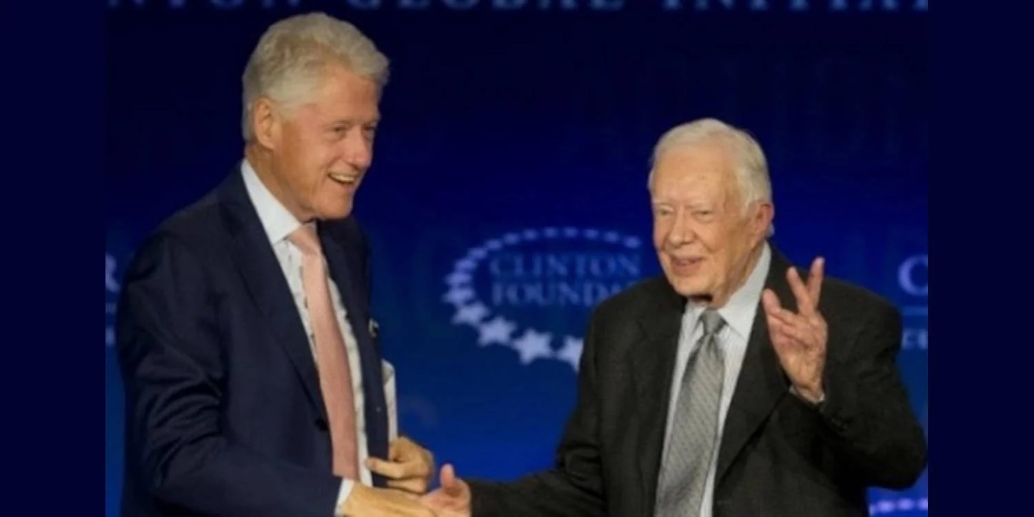 President Bill Clinton and former President Jimmy Carter shake hands.