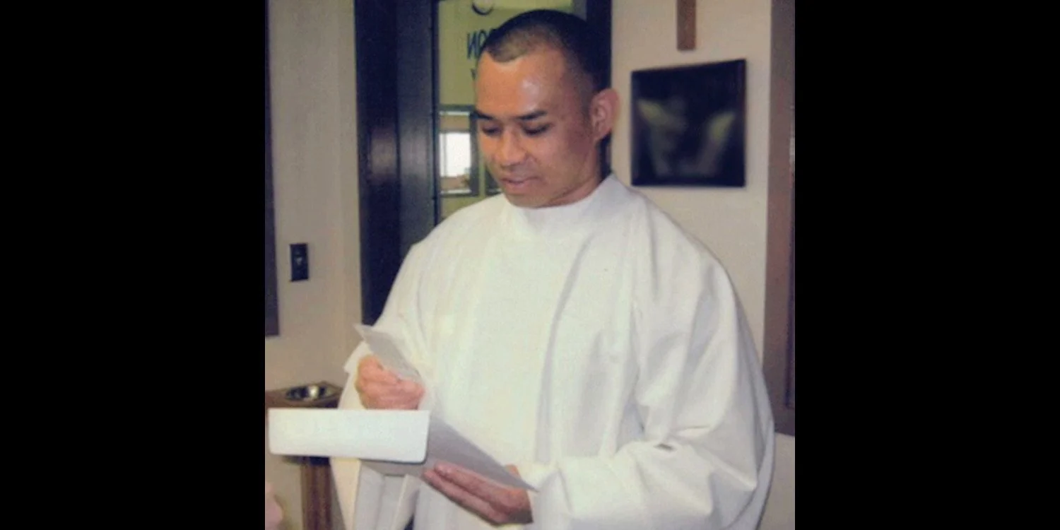 Pornchai Moontri in an alb after his Baptism looking at a card.