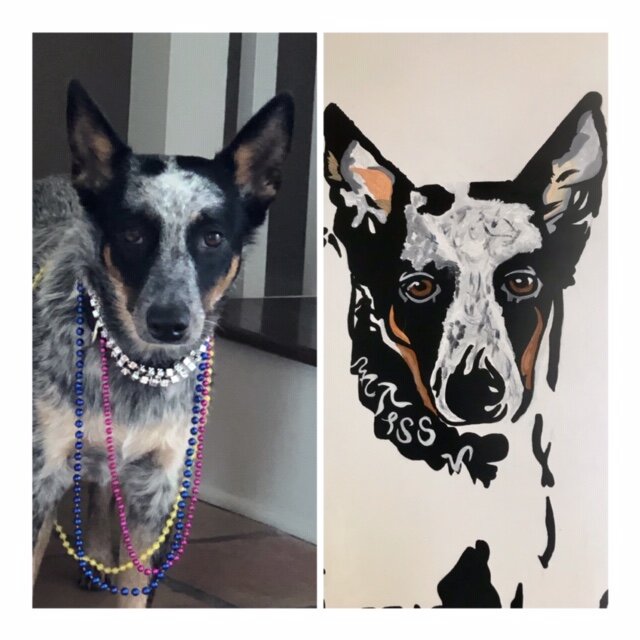 Side-by-side photo of a dog and a painted portrait of the same dog. The dog has black, gray, and tan fur, and is wearing multiple colorful bead necklaces. The painted portrait mimics the dog's appearance in a stylized, simplified black, white, and ta