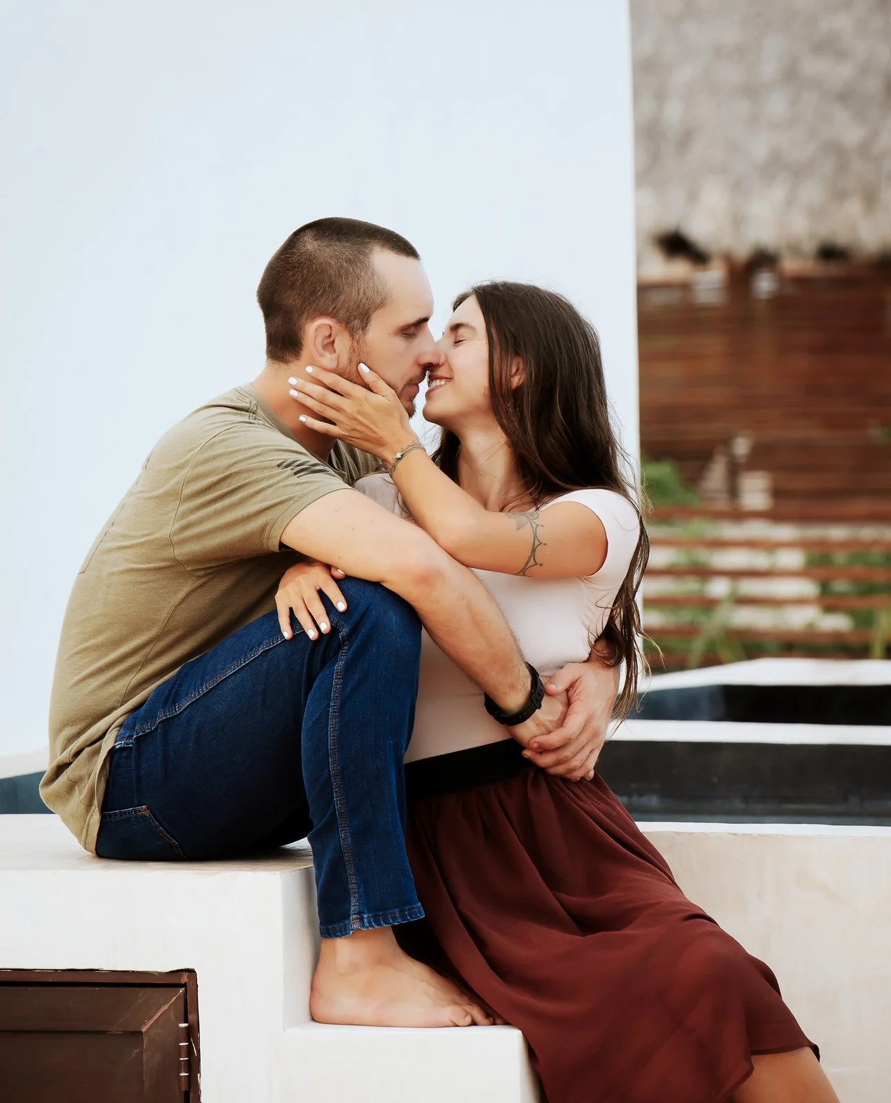 A couple sitting closely together, about to kiss, with their faces touching and eyes closed in Tulum, Mexico.