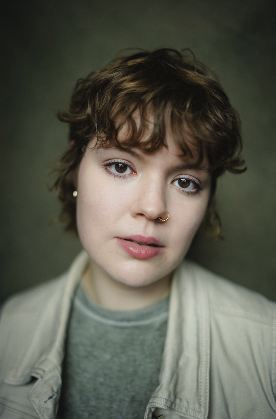 Headshot of Emily Wallenburg. Emily is a white younger woman between the ages of 18-30. She has light brown wavy hair and is wearing a green top.