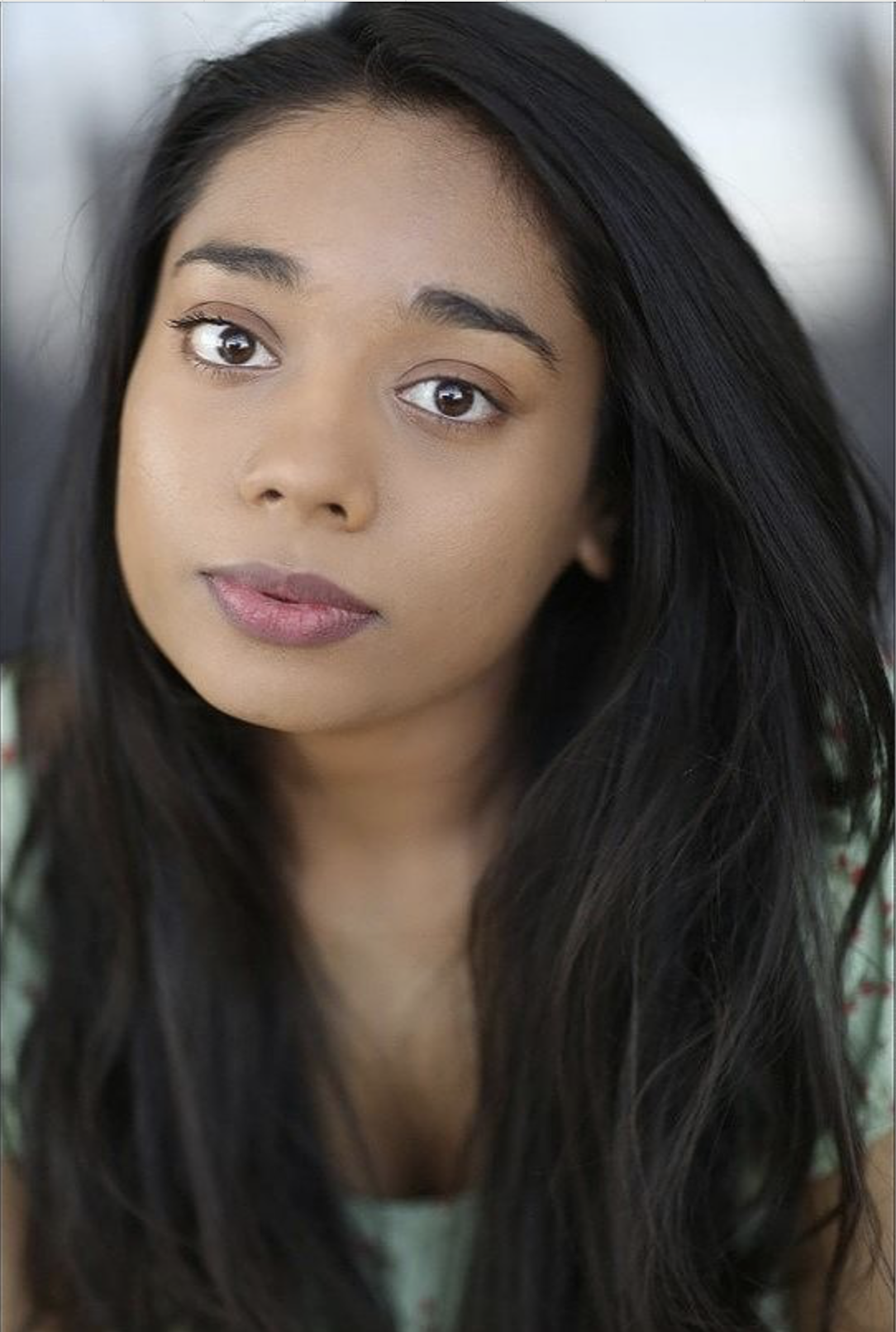 Headshot of actor Lucinda Nicole. Lucinda is a young British south asian female with brown eyes and dark brown-black/curly sometimes and straight other days, long hair.