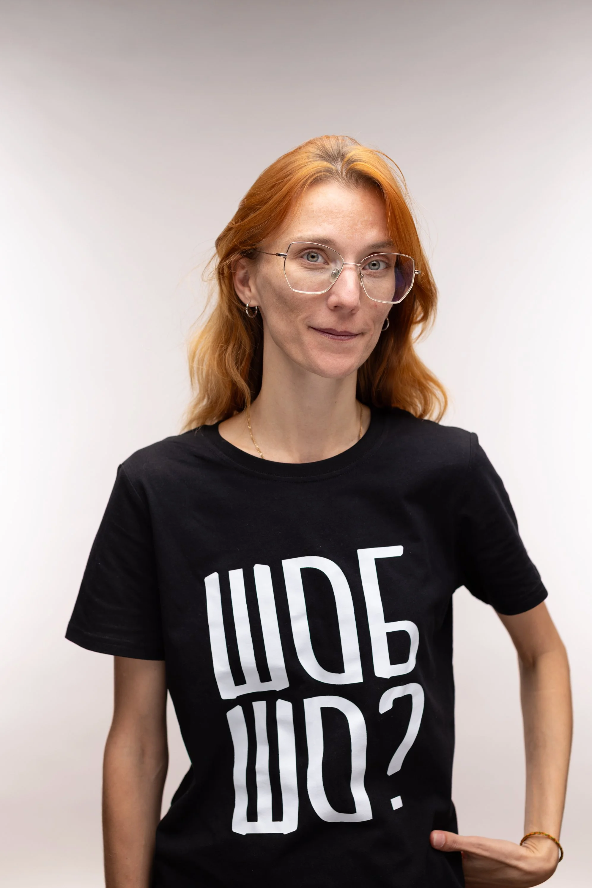 A woman with red hair and a black t-shirt posing in front of a white backdrop in Monika M. Kubiak photography studio in Leonberg Stuttgart