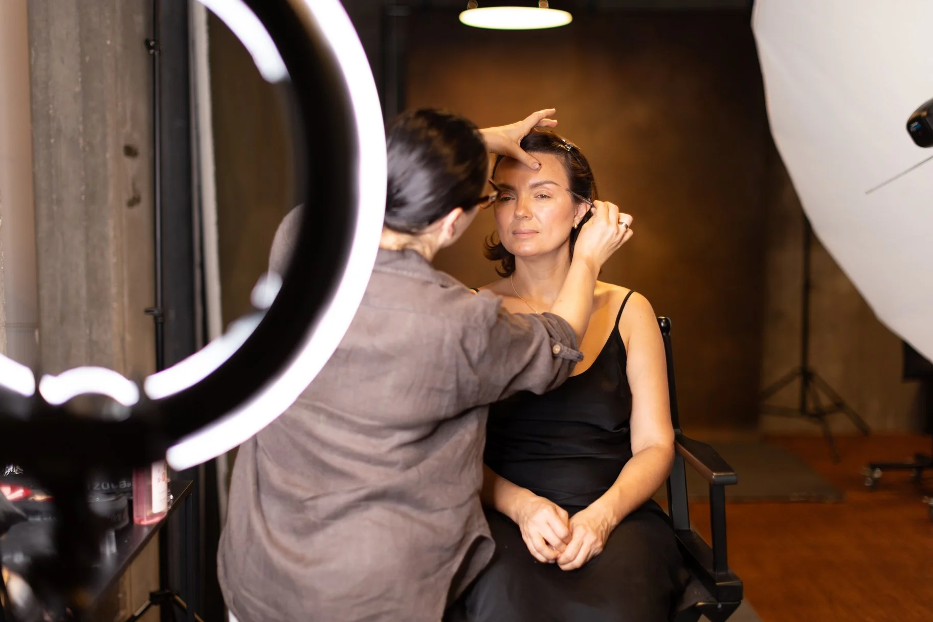 A MUA styling a client in a portrait photography studio for women in Leonberg.