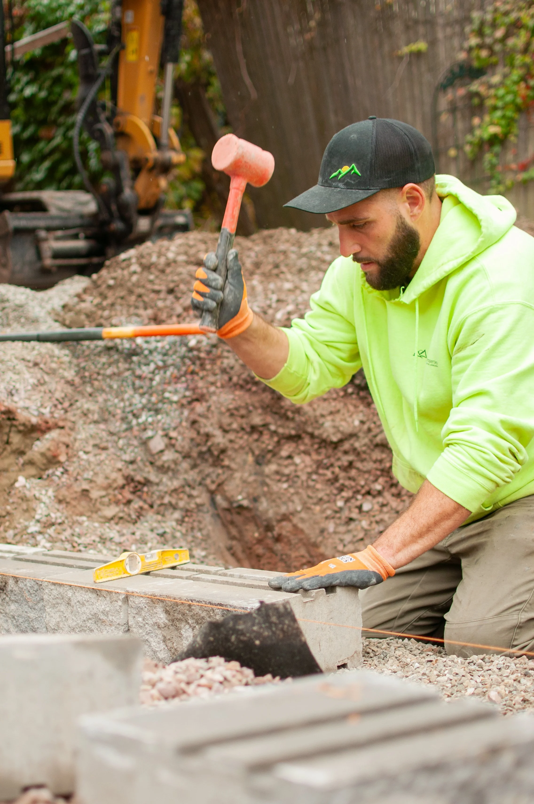 A person using a mallet to install a retaining wall as a part of a full backyard makeover.