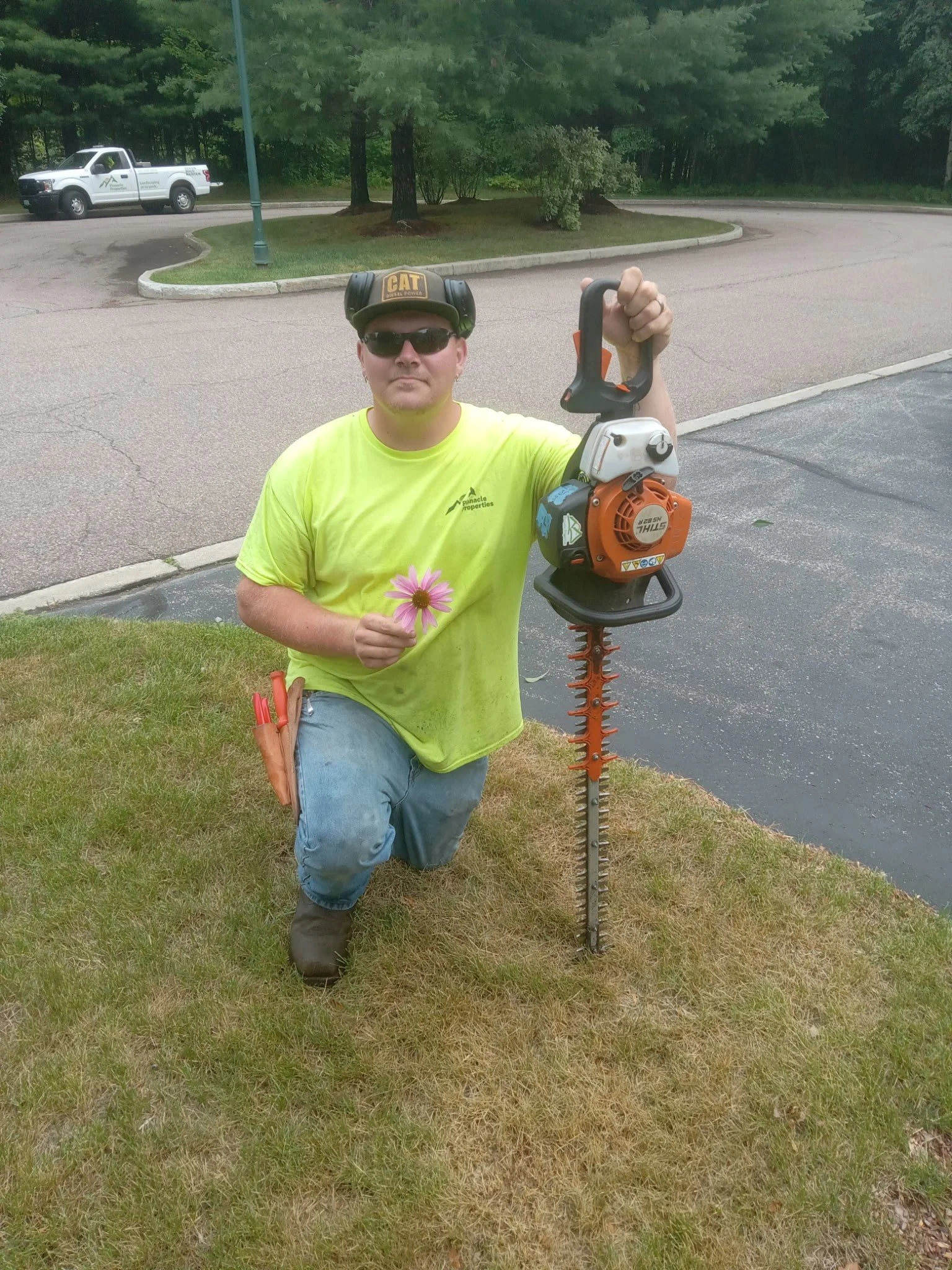 Man kneeling with a pruner in one hand and a flower in the other.