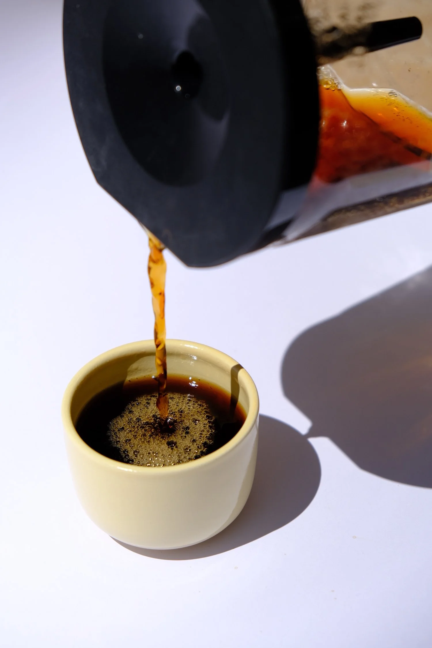 coffee poured into cappuchino cup in butter yellow