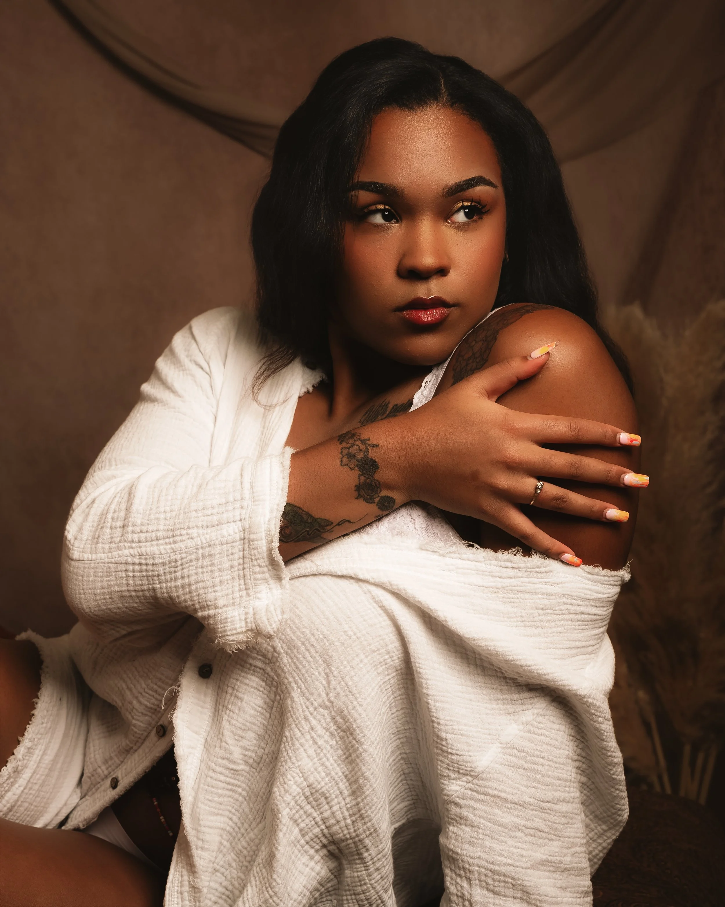 Elegant boudoir portrait of a woman wrapped in a soft white sweater, featuring intimate posing and warm studio lighting by South Jersey boudoir photographer Michael Rocco.