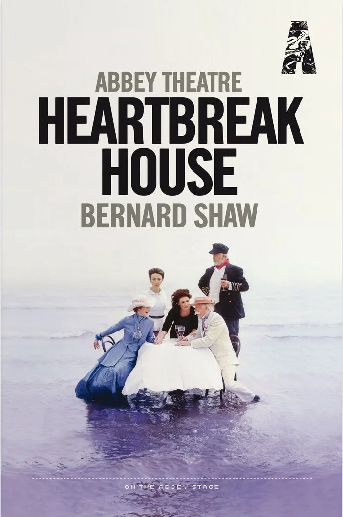 Poster for the play "Heartbreak House" by Bernard Shaw at Abbey Theatre, featuring five characters standing in shallow water with a dining table and chairs, dressed in early 20th-century attire.