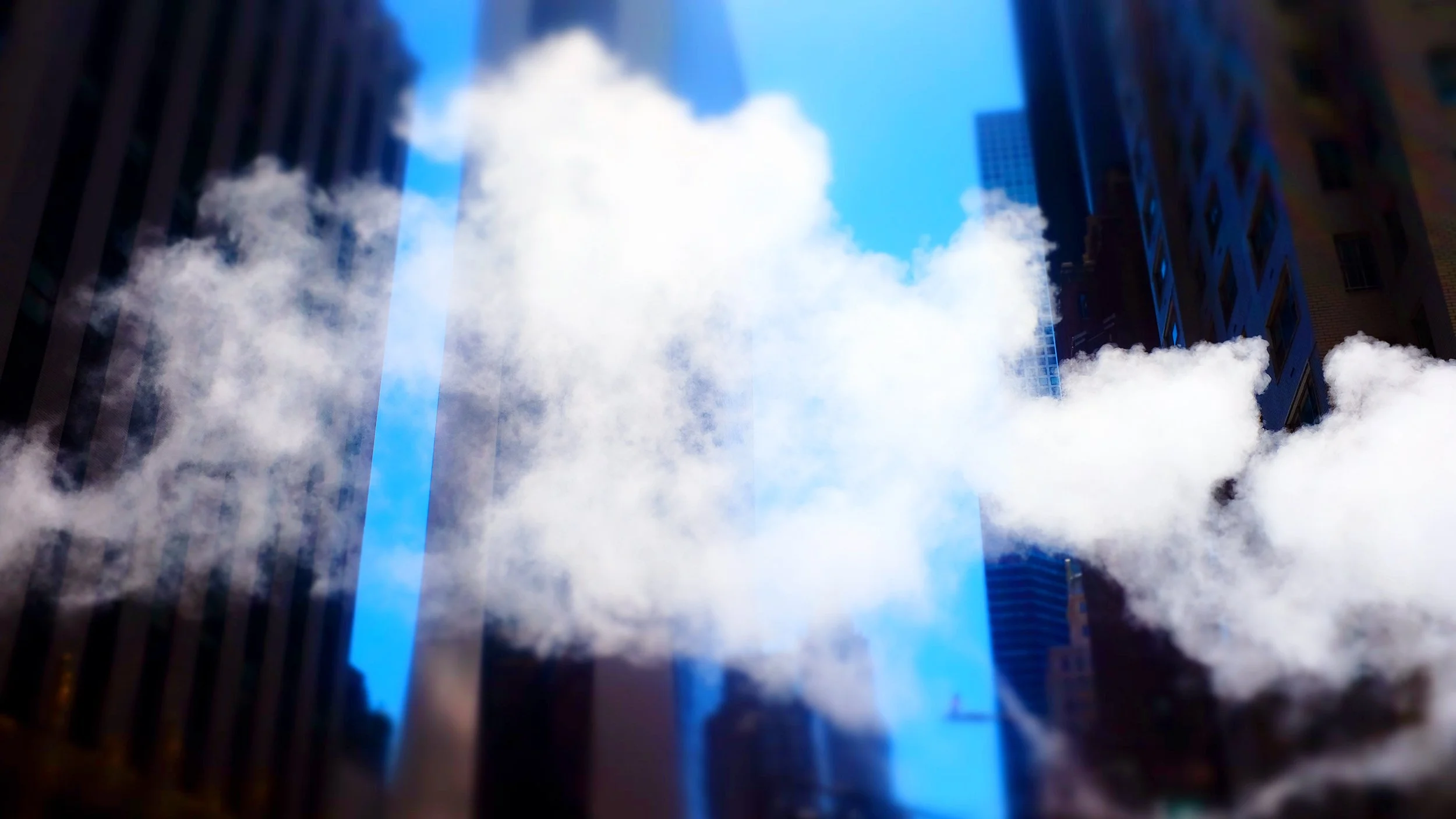View of the sky through a narrow opening between two tall buildings, with clouds and blue sky visible.