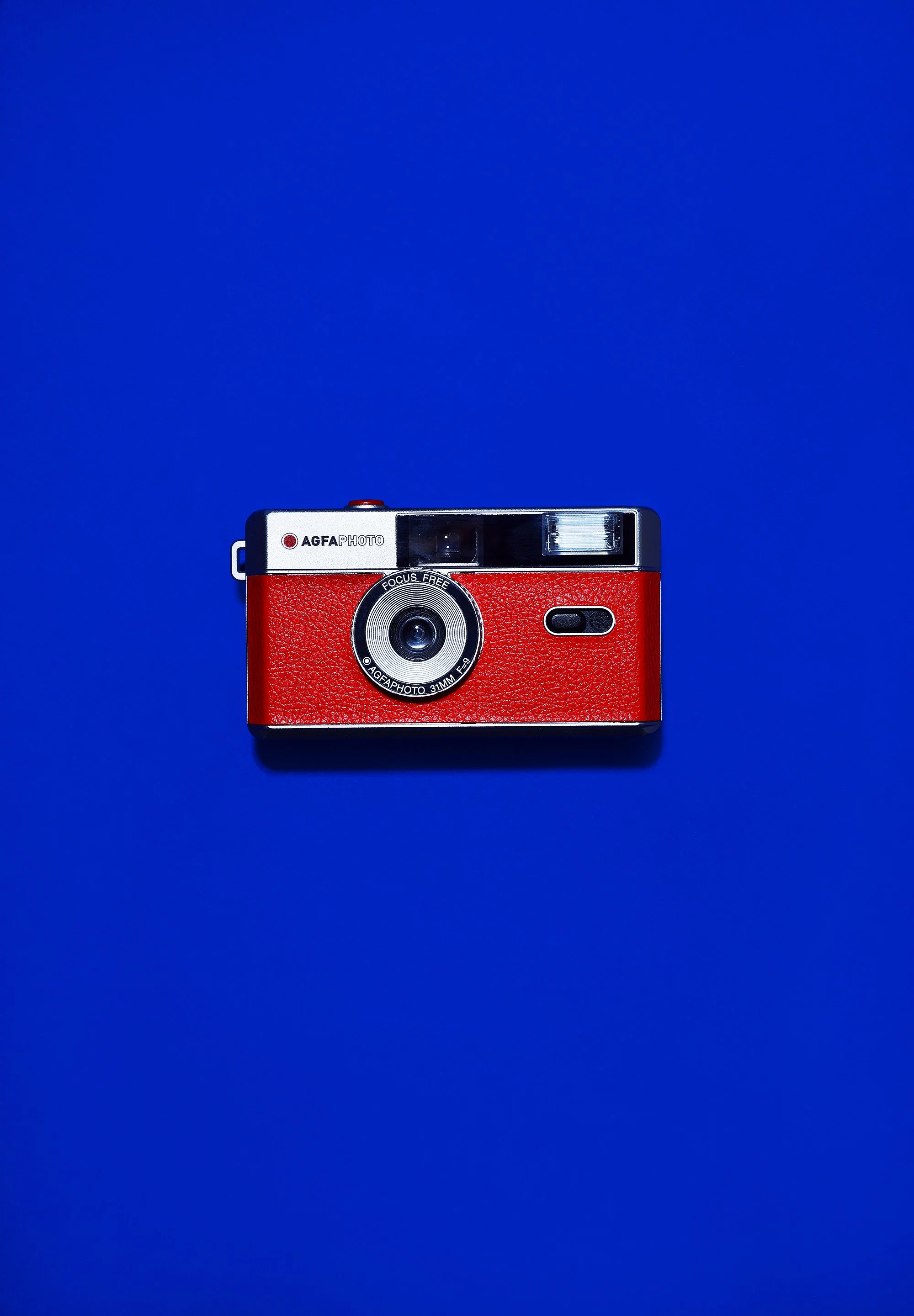 A vintage red and black camera placed on a blue background.