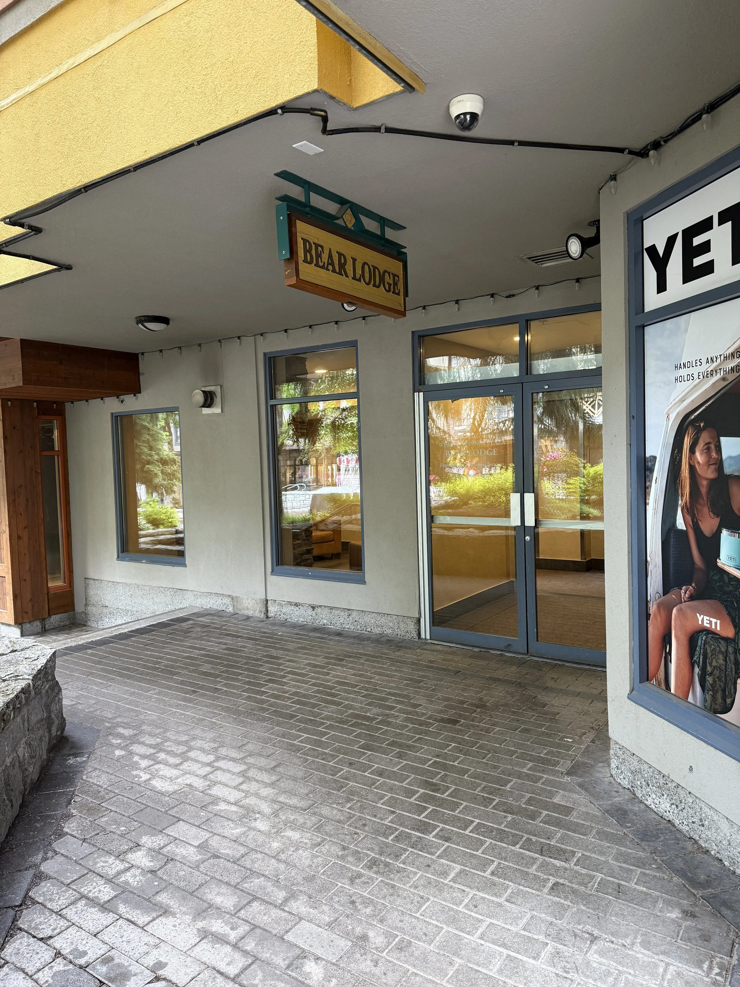 Exterior of a building with a sign reading 'Bear Lodge' and large window displays, including an advertisement for YETI.
